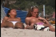 Deux copines topless simulent de baiser sur la plage